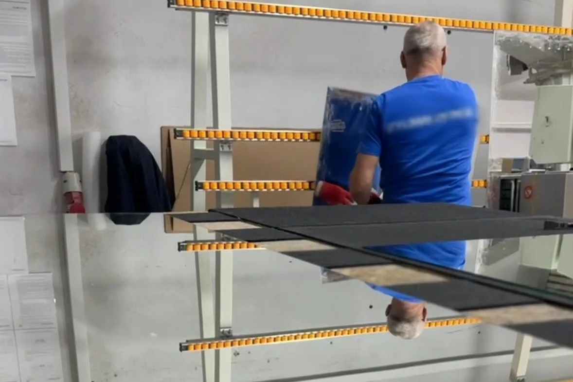 Mitarbeiter trägt eine große Spiegelplatte in der Werkstatt von Lumenic Mirrors